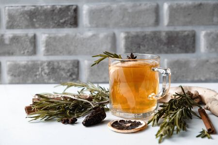 1 Cup of tea with rosemary, star anise, on a gray background, cone, slice of dried orange, ginger