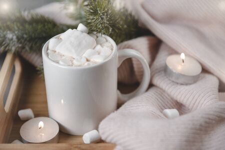 1 mug of cocoa, hot chocolate with marshmallows, spruce branch, candles with lights, side viewの写真素材