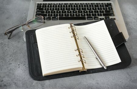 open diary with blank sheets, laptop, pen, glasses on a gray backgroundの写真素材