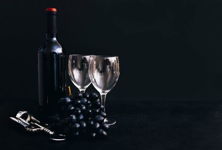 bottle of wine, 2 glasses, dark grapes, corkscrew on black background,  copy spaceの写真素材