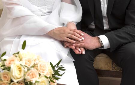 hands of bride and groom, wedding, bride in white dress, bouquet of beige rosesの写真素材