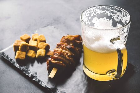 A mug of light beer with foam, smoked fish, crackers on a blackの写真素材