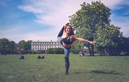 1 white young slender woman doing yoga in a Park on a Sunny dayの写真素材