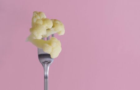 cauliflower on a fork on a pink backgroundの写真素材