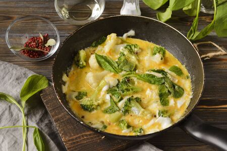fried eggs 4 eggs with spinach and broccoli in a pan top view