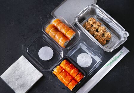 set of sushi and rolls with delivery in containers, Philadelphia rolls with salmon, California with caviar, baked with eel, Japanese food on a black backgroundの写真素材