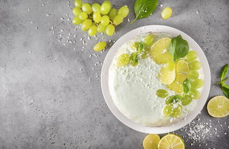 1 cake, pie  with grapes, lime slices,  green Basil, coconut shavings on a gray , baking, cream,  top view, citrus, copy space,の写真素材