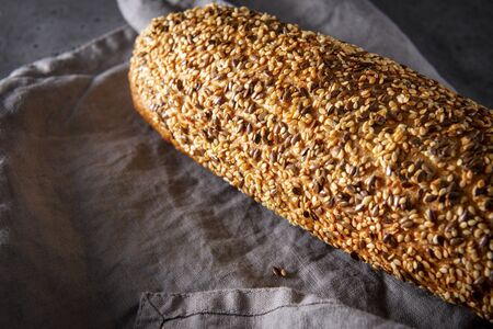 1 loaf of fresh grain bread on a gray towel on a gray background close-up, food, top view