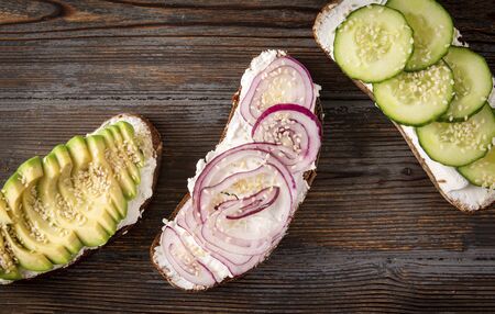 3  sandwiches with cheese, avocado, onion, cucumber and sesame on a dark wooden background, Breakfast, snack,  top view,の写真素材