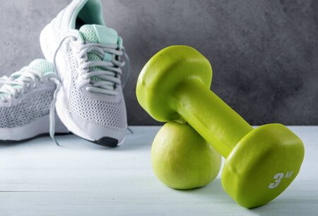 1 green dumbbell,  Apple, gray sneakers on a gray backgroundの写真素材