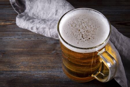 alcoholic beverage , 1 glass of light barley beer with foam on a gray napkin on a dark wooden background,  top viewの写真素材