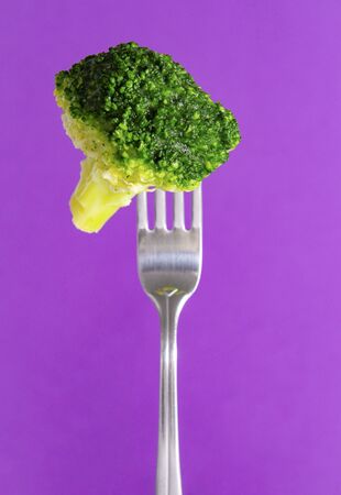 fresh green broccoli on a fork on a lilac background, vegetablesの写真素材