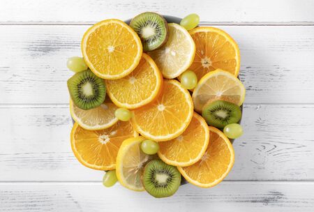 orange slices, lemon, green grapes, kiwi, on a white background ,fresh citrus and fruit, top view,の写真素材