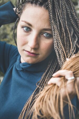 portrait 1 young beautiful white woman with African pigtails on a background of greenery close upの写真素材