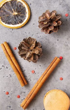 cinnamon sticks, cones,  slice of dried orange, beige French macaroon cookies on a gray background,の写真素材