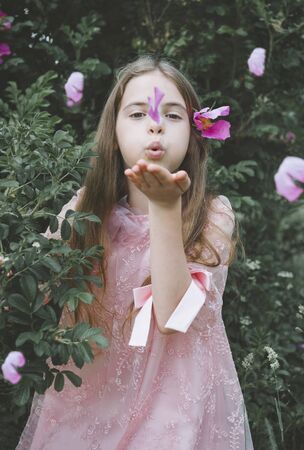 1 white girl 10 years old in a pink dress among the greenery with pink petalsの写真素材