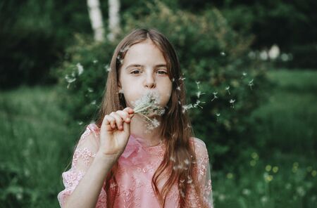 1 white girl 10 years old in a pink dress with dandelions on a green backgroundの写真素材