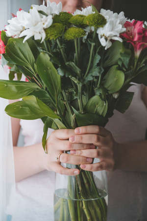 1 woman holds a vase of flowers on a dark backgroundの写真素材