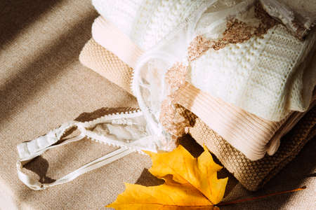 light knitted sweaters, white bra, yellow maple leaf on beige sofa