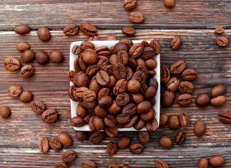 roasted brown coffee beans in a bowl on a dark wooden background top view close up