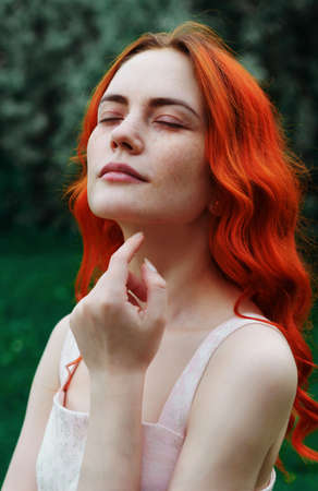 young beautiful woman with red hair and freckles on a green background