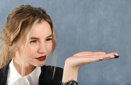 1 white young blonde woman in a white shirt holds her hand in front of her, pointing at an object on...