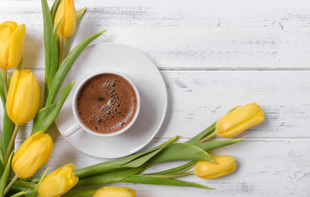 lots of yellow tulips, a cup of black coffee on a white wooden background, gift, flowers, top viewの写真素材