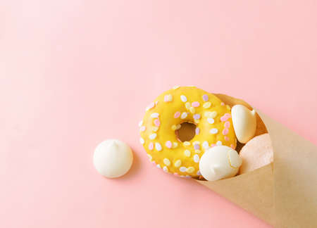 yellow donat and white meringue cookies in a paper envelope on a beige background top viewの写真素材