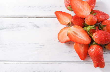 ripe red strawberries with on a white wooden background top view