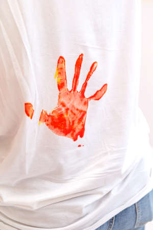 child's hand print in red paint on the back of a white T-shirtの写真素材