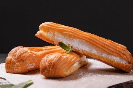3 eclairs with powdered sugar on a dark background, dissert,