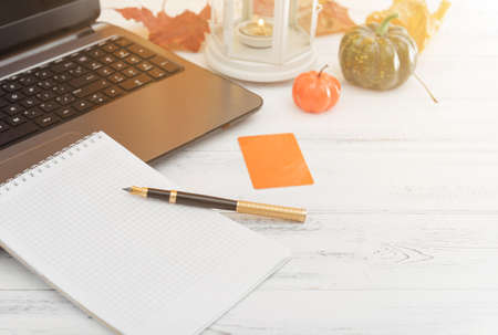 autumn composition, pen, laptop, notebook, pumpkin on a white background