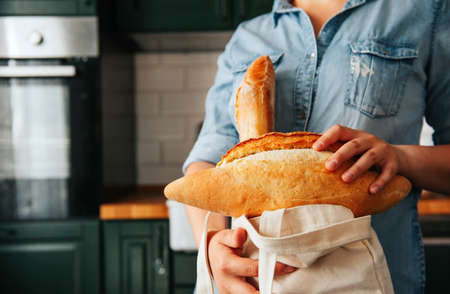 woman in a blue shirt with bread in a bag in the kitchen, a person and food