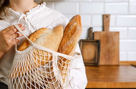 1 woman in a white blouse with bread in a bag in the kitchenの写真素材