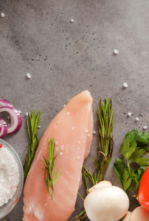 raw chicken fillet with rosemary, onion, salt, mushrooms top view on a gray backgroundの写真素材