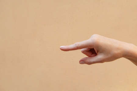 A female finger pointing aside on a brown backgroundの写真素材