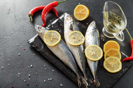 3 raw fish, mackerel,  lemon, red chili pepper, olive oil  on a dark background, seafoodの写真素材