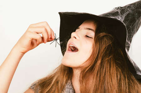 Cute white little girl in witch's hat holding spider face halloweenの写真素材
