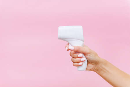 Woman's hand holding white thermometer on pink background horizontal copy spaceの写真素材