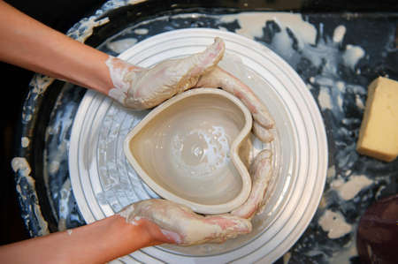 Woman white hands doing pottery top view pottery wheel horizontal no face close upの写真素材
