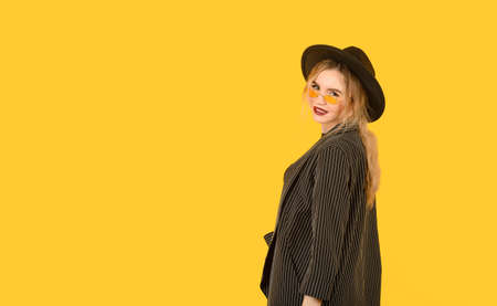 Young girl posing on yellow background half body direct look back side view brown clothes yellow...
