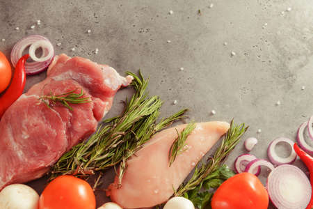 raw chicken fillet with rosemary, pork tenderloin, mushrooms, tomato, chili pepper, onion, top view on a gray backgroundの写真素材