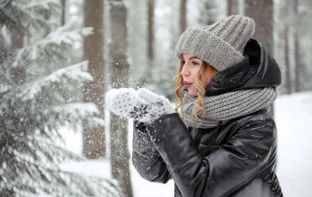 European woman holds snow in her hands in the forest in winterの写真素材