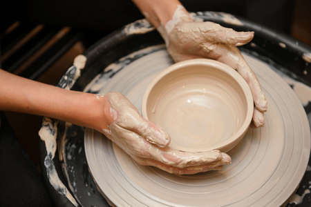 Woman's hands making ceramic on a pottery circle close up minimalisticの写真素材
