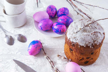 Easter cake with purple eggs and willow branches side look white cups table cloth spring festive...
