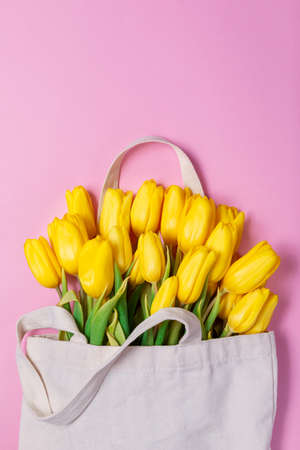 Yellow tulips in shopper on pink background vertical spring floral minimal bouquetの写真素材
