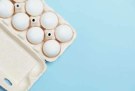 White eggs in cardboard on light blue background spring fresh productsの写真素材
