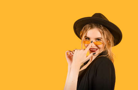 1 young white woman in a black jacket, sunglasses and hat smile on a yellowの写真素材