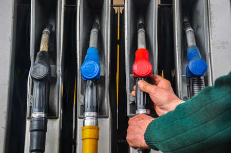 Man's hands taking automotive refueling gun at gas station.の写真素材