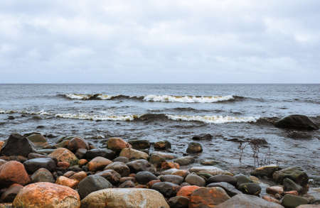 Stones on the shore of stormy waving Ladoga lake. Priozersk, Russia.の写真素材